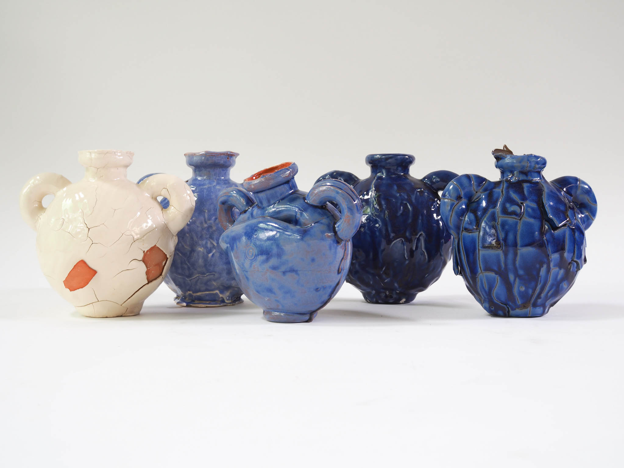 collection of ceramic vases in different shades of blue and with different sizes of cracks